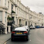 a row of typical british townhouses with cars parked along the street